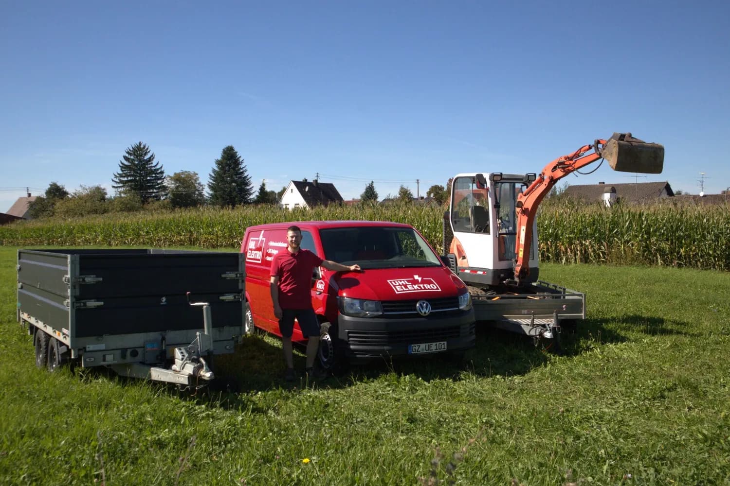 Andreas Uhl mit Transporter, Minibagger und Kipper-Anhänger auf einer Wiese